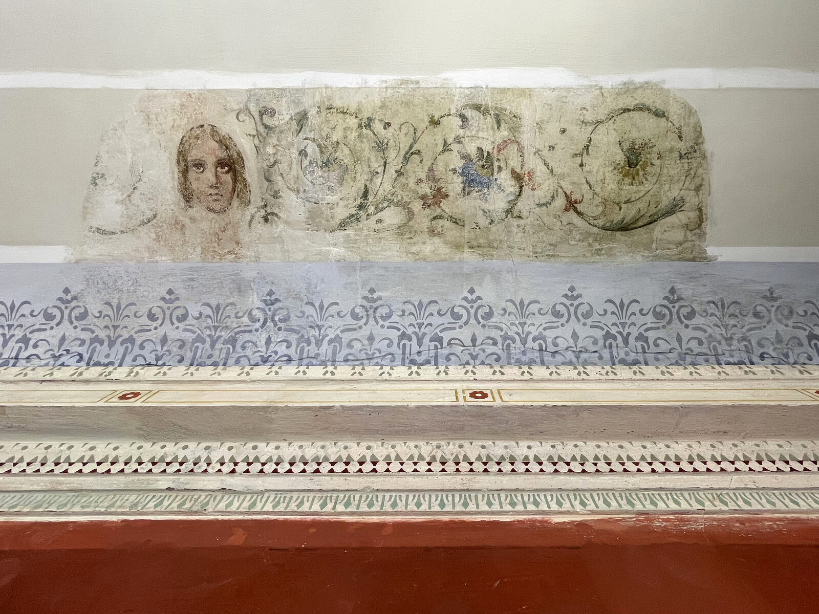 Freigelegtes Wandmalerei-Fragment mit figürlicher Darstellung, Rankenwerk und darunterliegender Schablonenmalerei